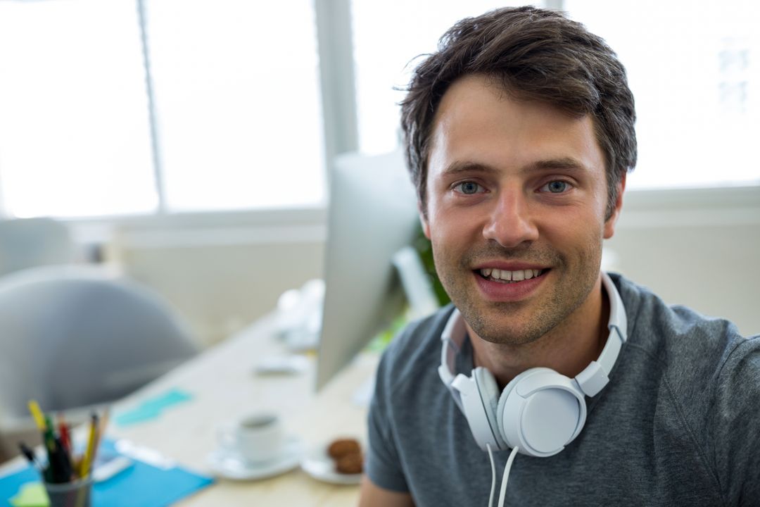 Young Professional Smiling in Modern Office with Headphones