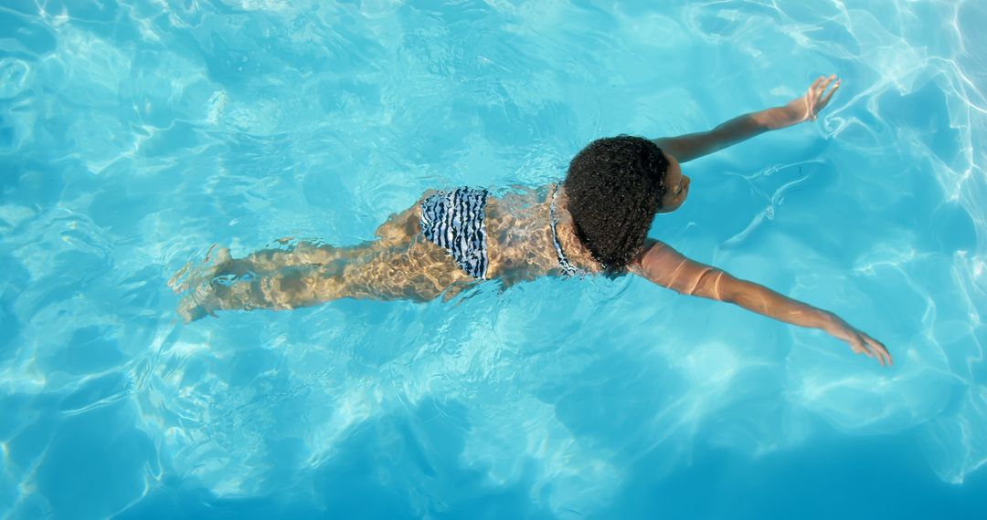 Young child swimming in pool with blue water on sunny day - Free Images, Stock Photos and Pictures on Pikwizard.com