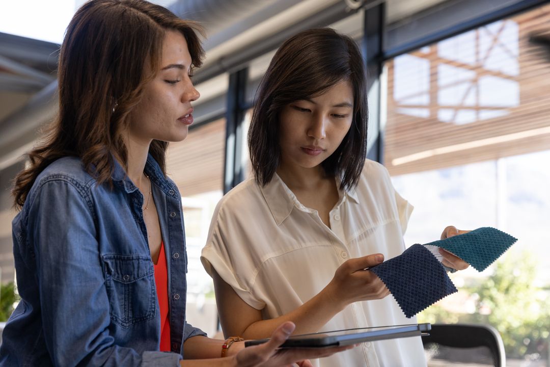 Diverse Colleagues Examining Fabric Swatches with Tablet in Studio