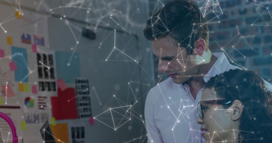 Collaborating team analyzing data on laptop with digital network overlay in creative office