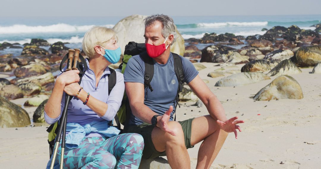 Senior Hikers Relaxing on Coast with Face Masks and Hiking Gear