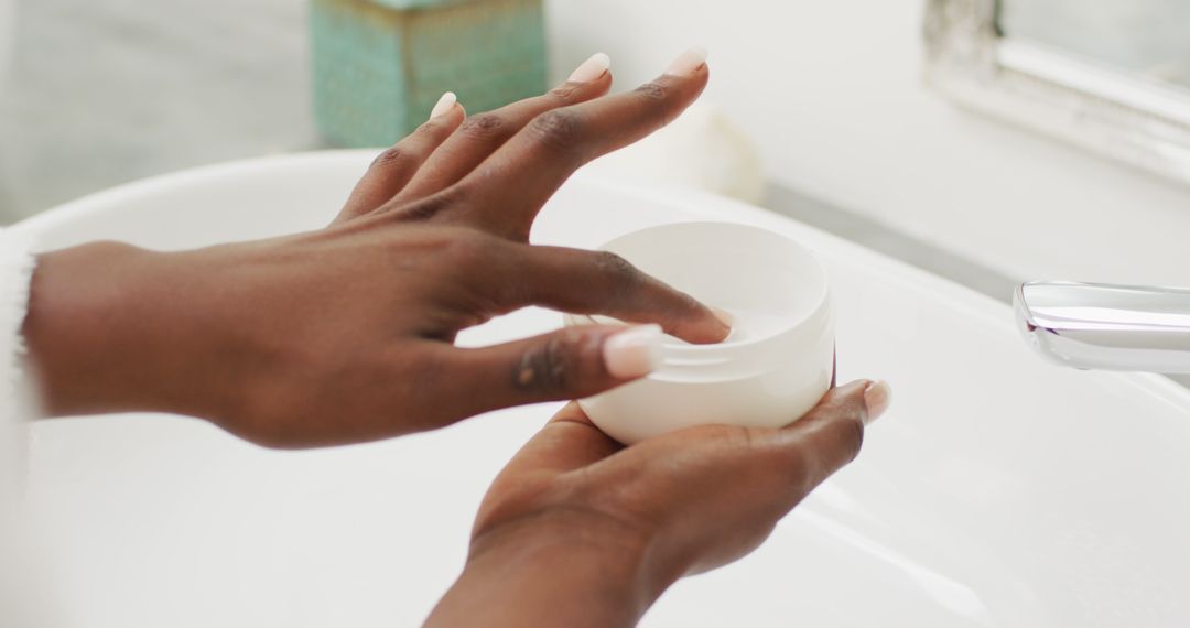 Woman Applying Moisturizing Cream to Hands in Bathroom - Free Images, Stock Photos and Pictures on Pikwizard.com