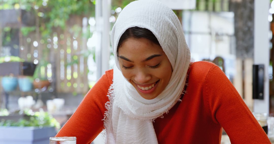 Smiling Muslim Woman in White Hijab Relaxing in Outdoor Cafe - Free Images, Stock Photos and Pictures on Pikwizard.com