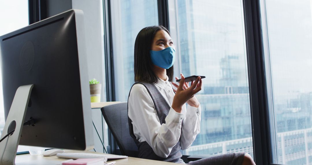 Businesswoman Wearing Face Mask Talking on Smartphone in Modern Office - Free Images, Stock Photos and Pictures on Pikwizard.com