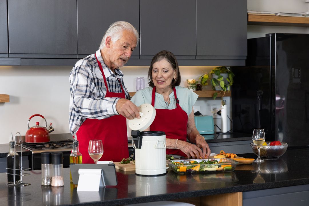 Senior Couple Operating Food Processor and Preparing Vegetables in Modern Kitchen