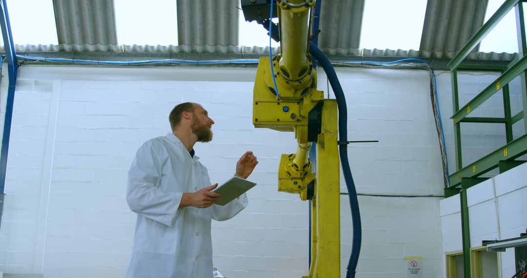 Engineer Inspecting Industrial Robot with Tablet in Factory - Free Images, Stock Photos and Pictures on Pikwizard.com