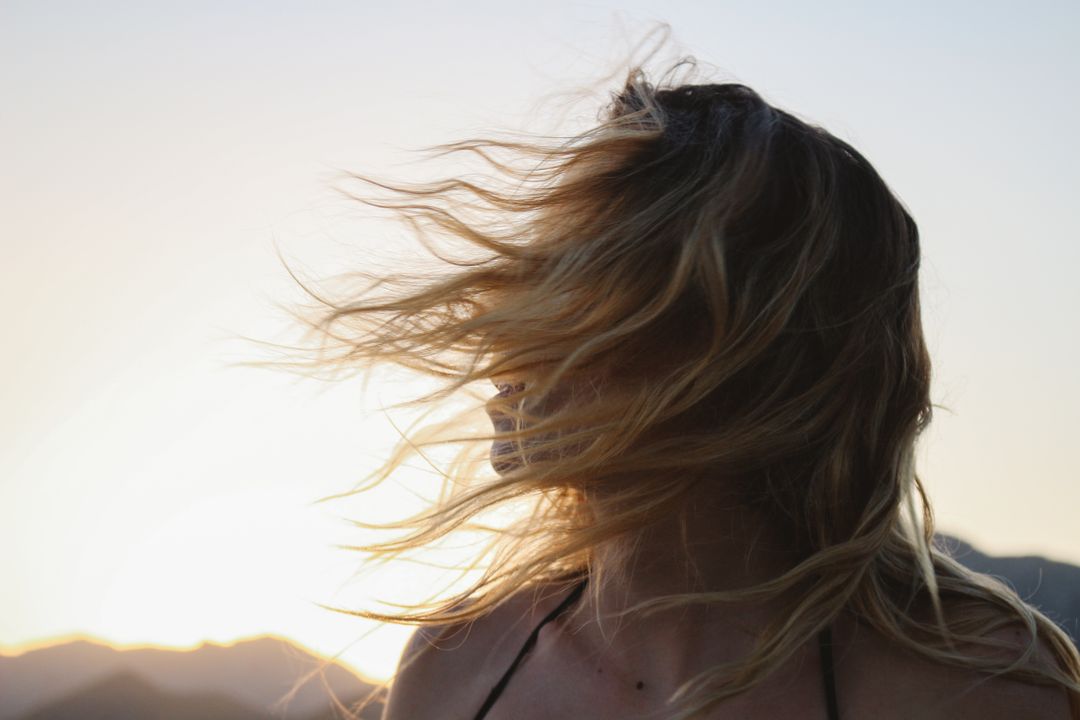 Woman with Windblown Hair Enjoying Sunset Outdoors - Free Images, Stock Photos and Pictures on Pikwizard.com