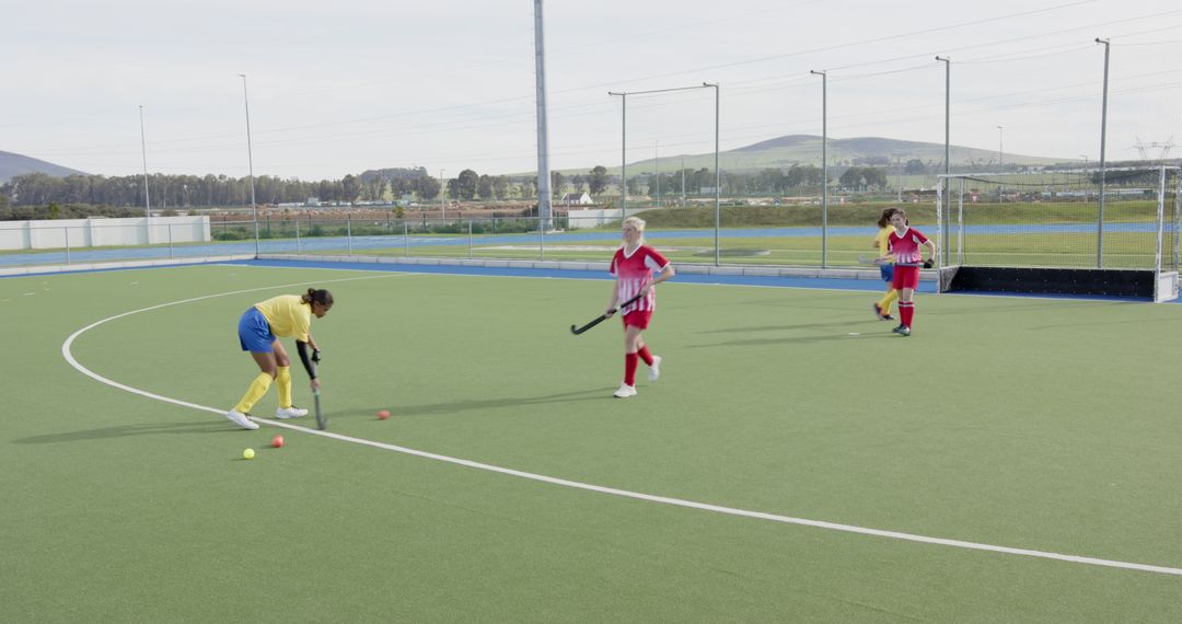 Teenagers Engaged in Dynamic Field Hockey Match on Turf Field