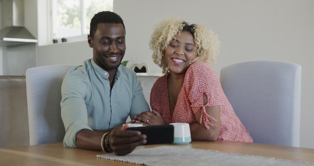 Couple Smiling While Watching Smartphone Together at Home
