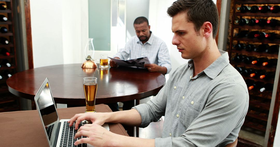 Young Man Working on Laptop with Beer in Modern Pub - Free Images, Stock Photos and Pictures on Pikwizard.com