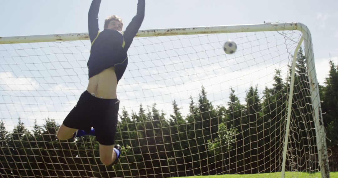 Goalkeeper leaping to save soccer ball during outdoor match - Free Images, Stock Photos and Pictures on Pikwizard.com