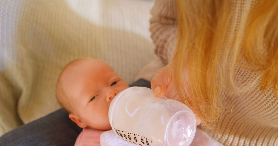 Caucasian Baby Feeding from Bottle Held by Adult Caregiver - Free Images, Stock Photos and Pictures on Pikwizard.com