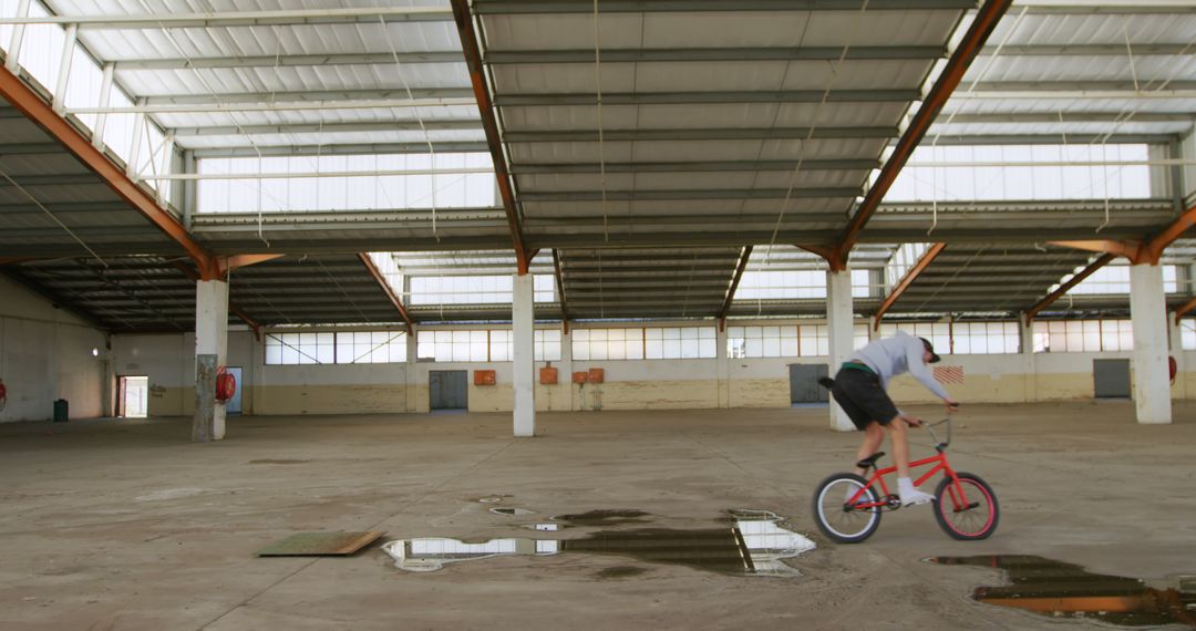 Man Riding BMX Bike Inside Empty Warehouse - Free Images, Stock Photos and Pictures on Pikwizard.com