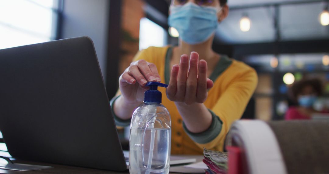 Office Worker Sanitizing Hands with Hand Sanitizer while Wearing Face Mask - Free Images, Stock Photos and Pictures on Pikwizard.com