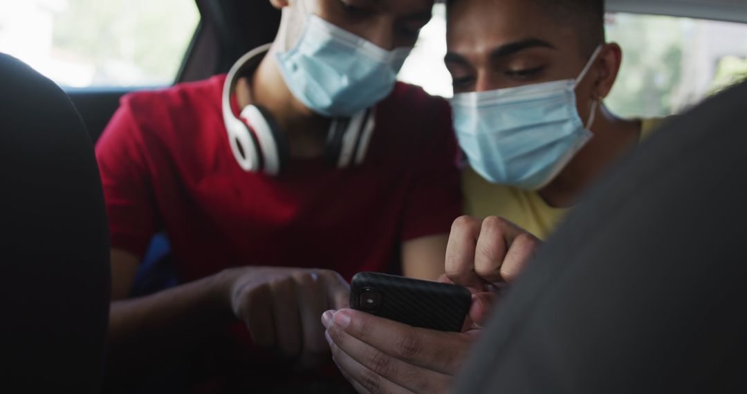 Two Friends Wearing Face Masks Using Smartphone in Cab