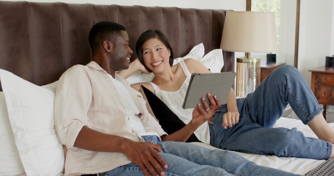 Happy Couple Relaxing on Cozy Bed with Tablet at Home