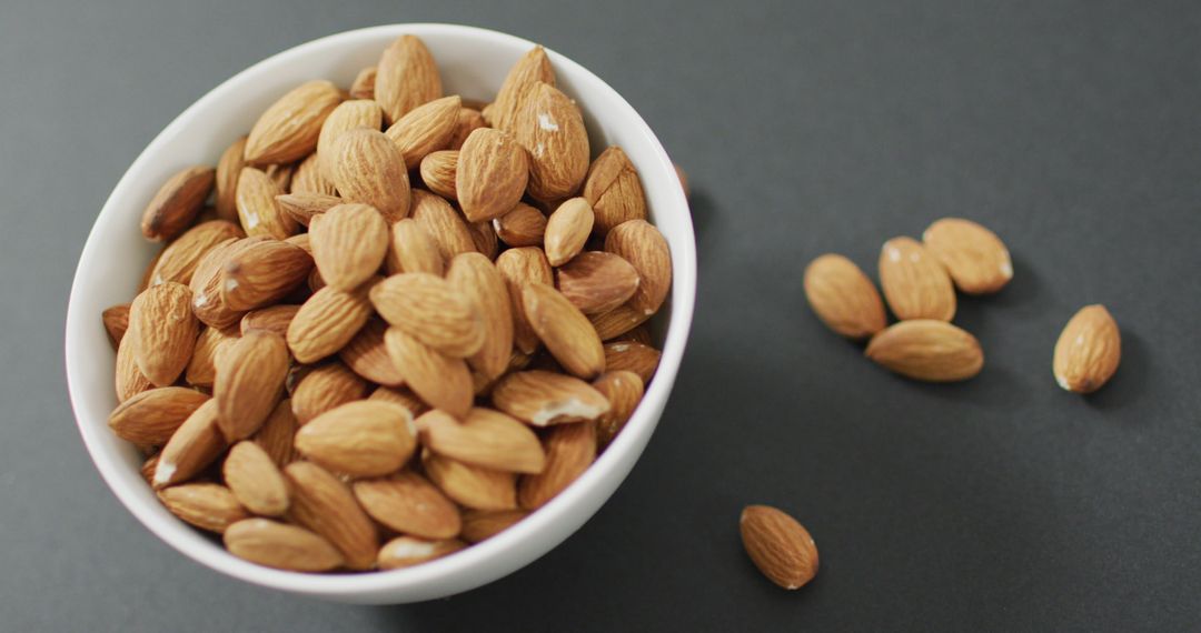Fresh Almonds in White Bowl on Grey Background