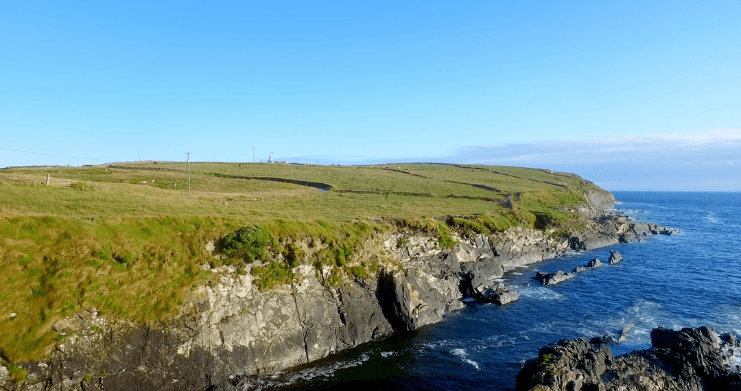 Transparent Cliffs with Lush Green Top Against Blue Sea Horizon