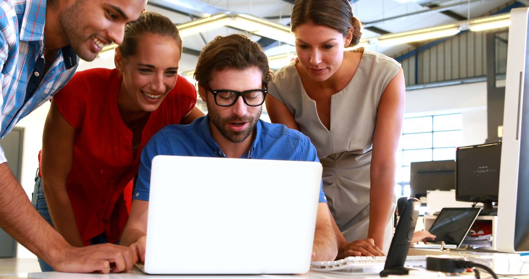 Team Collaborating on Project Around Laptop in Modern Office