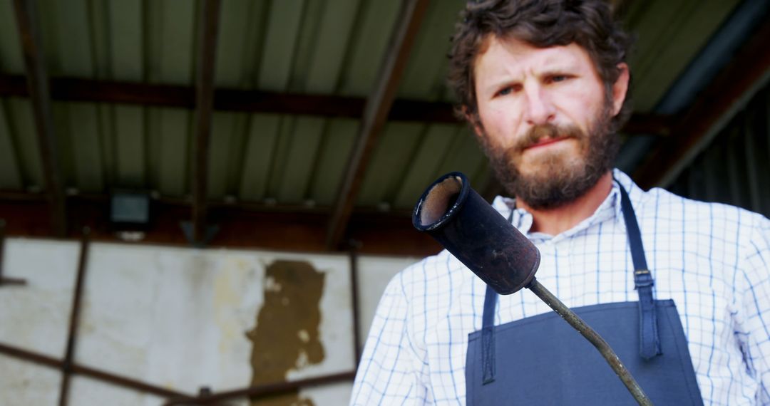 Bearded Man Holding Metal Pipe in Outdoor Workshop - Free Images, Stock Photos and Pictures on Pikwizard.com