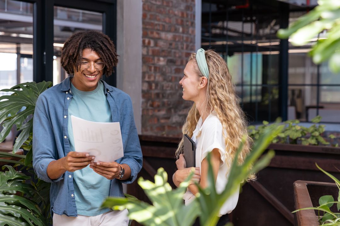 Diverse Colleagues Discussing Charts and Strategies in Green Office Setting