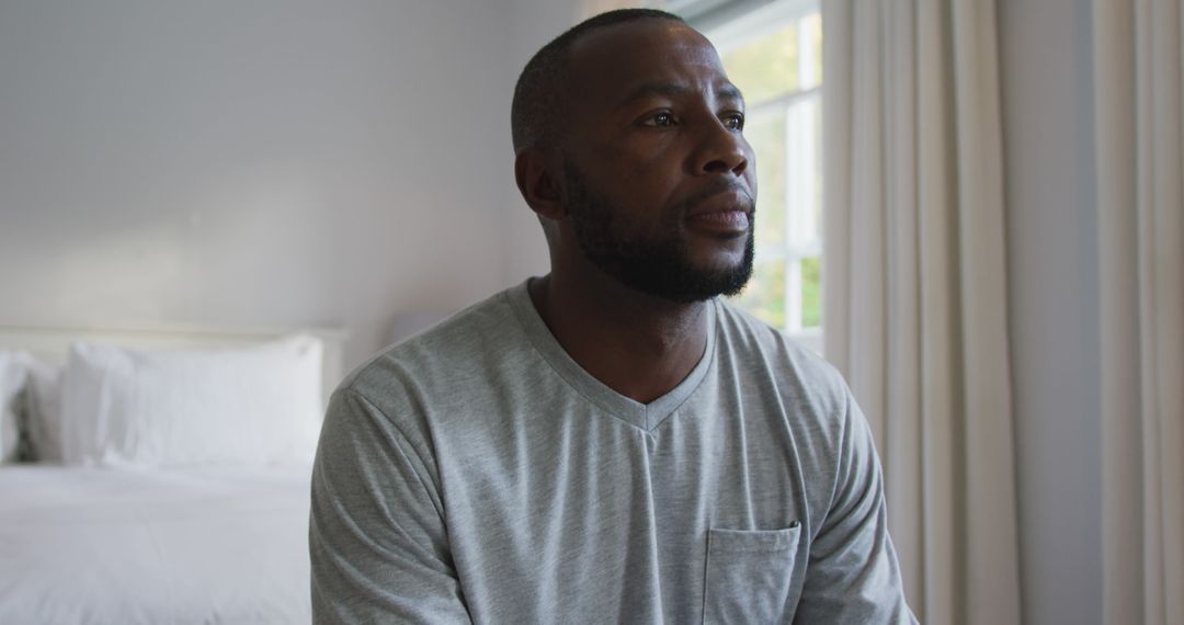 Thoughtful African American Man Sitting in Bedroom - Free Images, Stock Photos and Pictures on Pikwizard.com