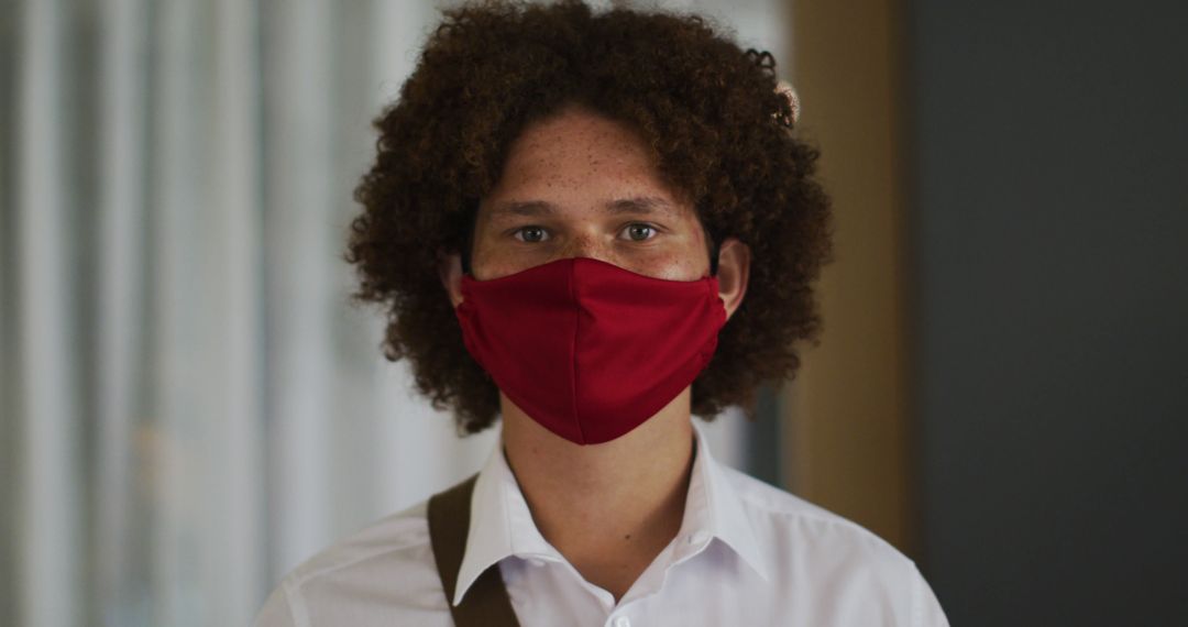 Portrait of biracial man with curly hair wearing red face mask - Free Images, Stock Photos and Pictures on Pikwizard.com