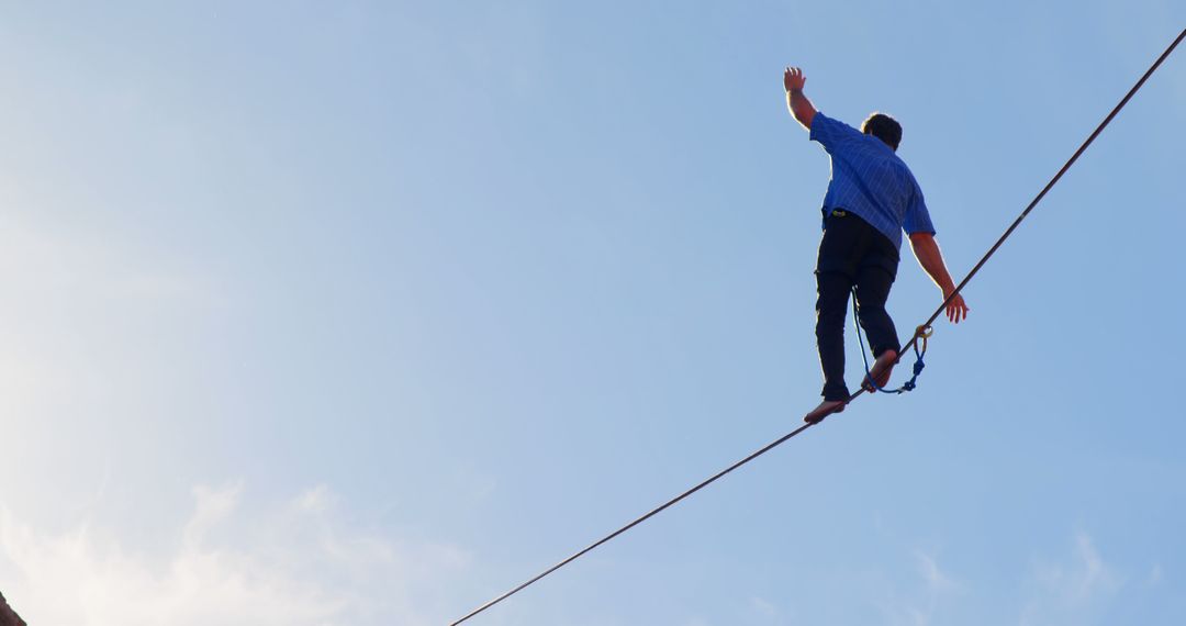 Man Balancing on Tightrope Against Clear Blue Sky - Free Images, Stock Photos and Pictures on Pikwizard.com