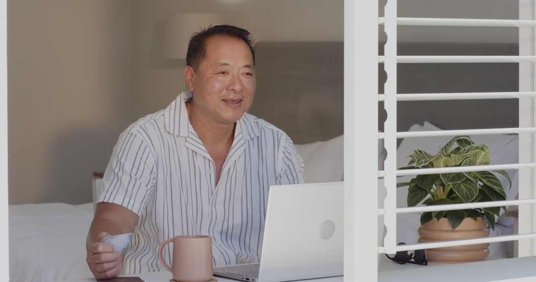 Asian Man Enjoying Remote Work from Home with Laptop and Coffee