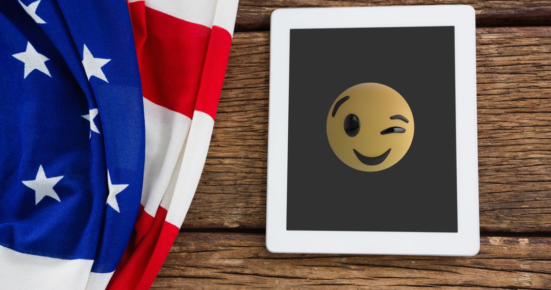 Tablet with Winking Emoji by American Flag on Rustic Wood