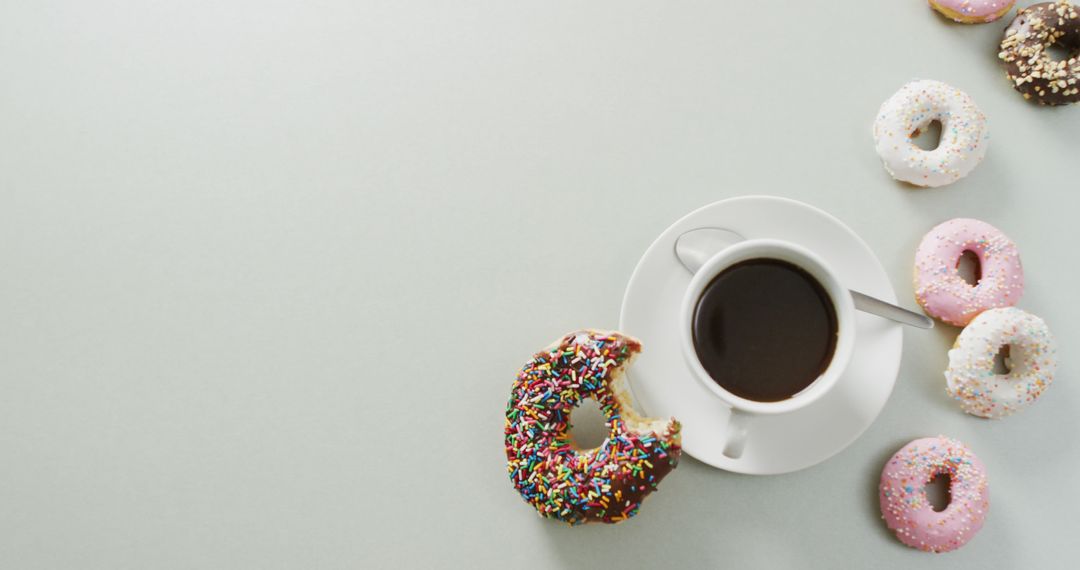 Image of donuts with icing and cup of coffee on white background - Free Images, Stock Photos and Pictures on Pikwizard.com