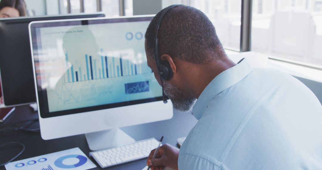 Man Analyzing Data on Computer with Headset in Office - Free Images, Stock Photos and Pictures on Pikwizard.com