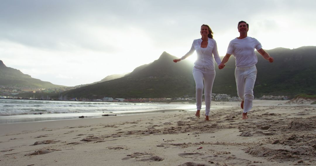 Happy Couple Running on Scenic Beach at Sunset - Free Images, Stock Photos and Pictures on Pikwizard.com
