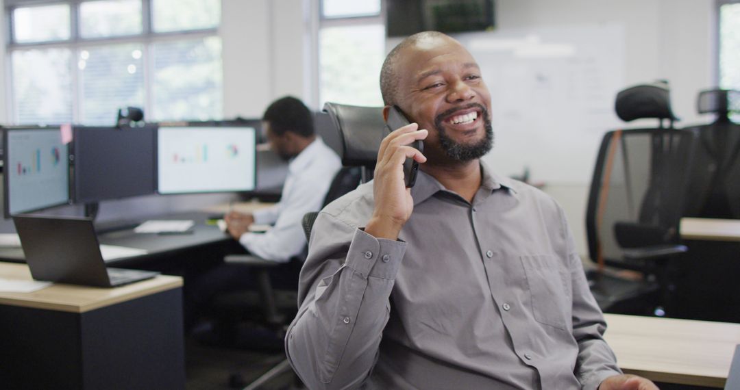 Smiling Man Talking on Phone in Modern Office Environment - Free Images, Stock Photos and Pictures on Pikwizard.com