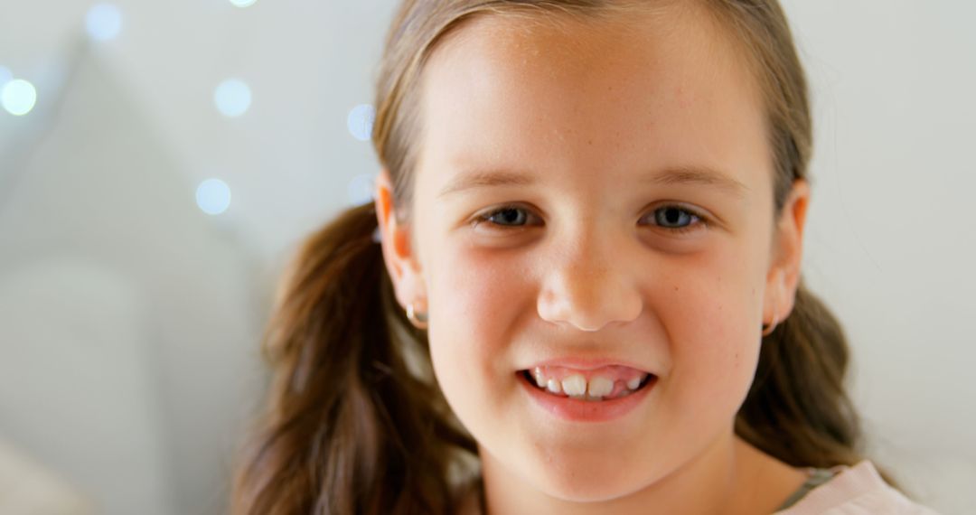 Smiling Young Girl with Pigtails and Fairy Lights in Background - Free Images, Stock Photos and Pictures on Pikwizard.com