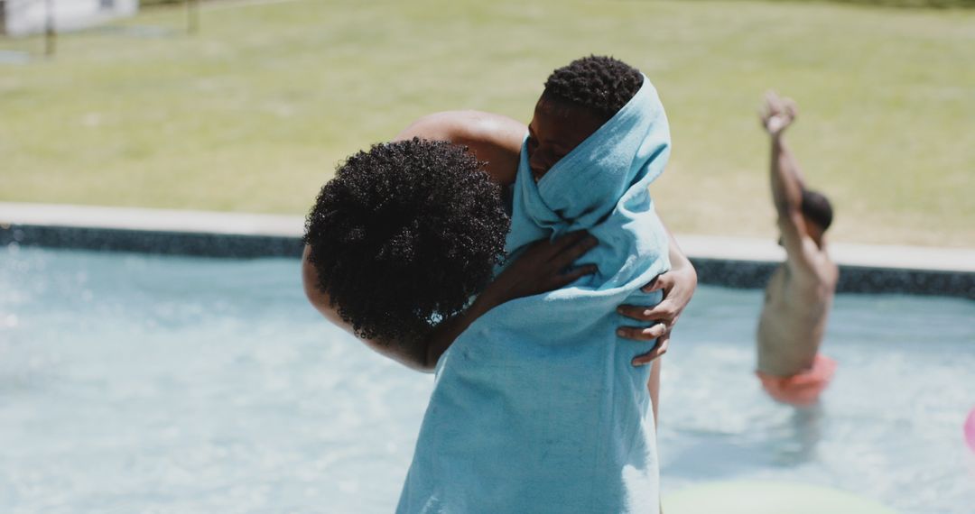 Mother Drying Son with Towel by Poolside on Sunny Day