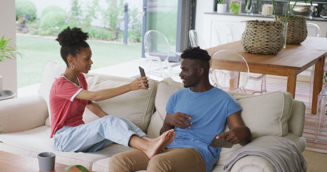 Young Couple Relaxing on Sofa Sharing Smartphone Interaction