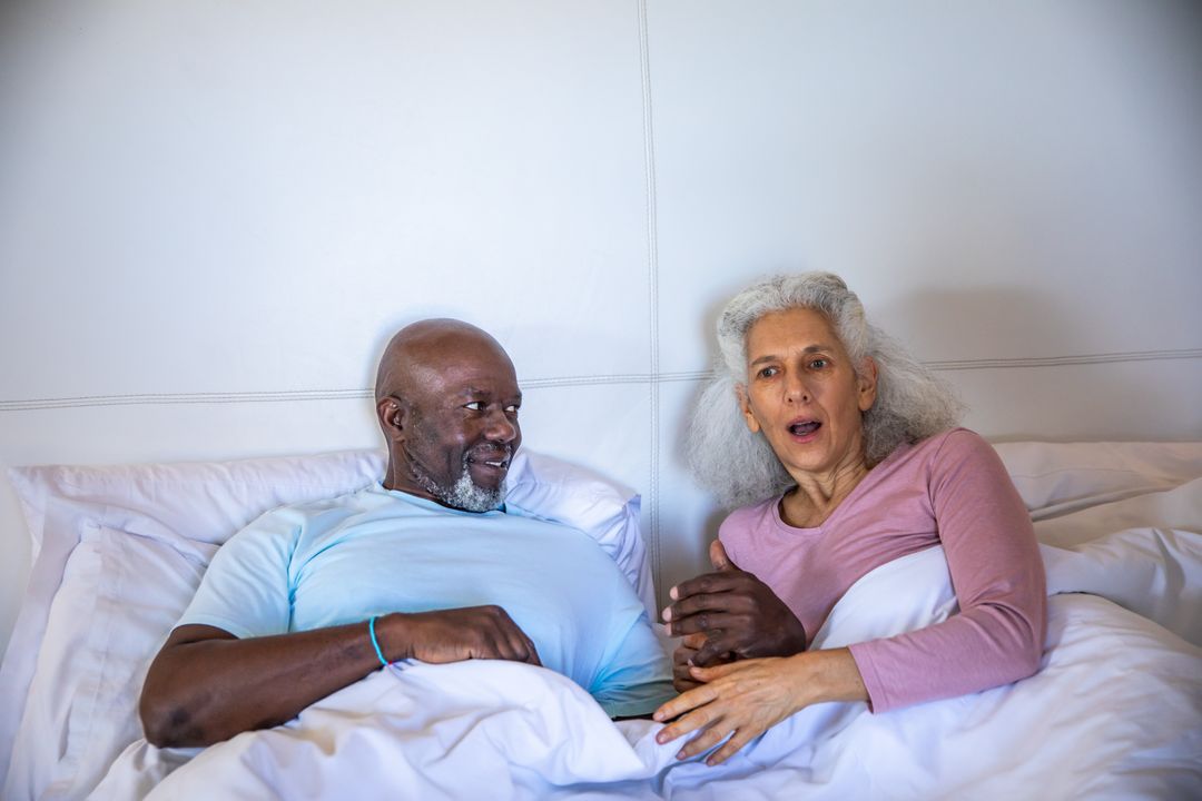 Diverse Senior Couple Showing Surprise and Affection in Bed