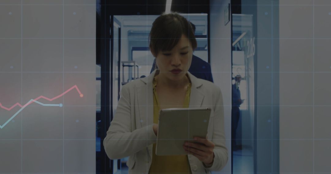 Asian Professional Analyzing Data with Tablet in Modern Office