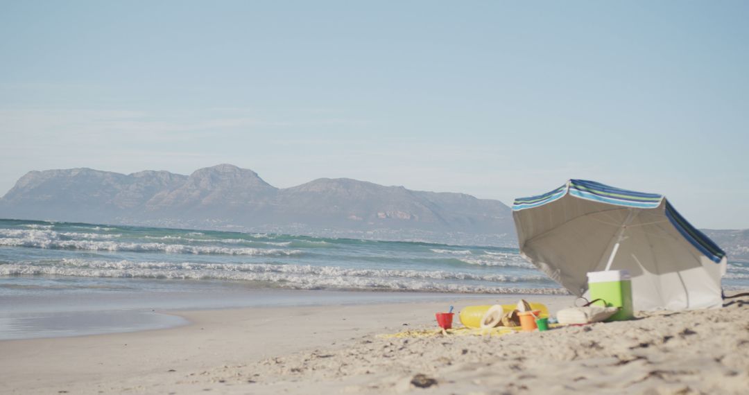 Abandoned Beach Setup with Umbrella, Cooler and Toys by the Seaside - Free Images, Stock Photos and Pictures on Pikwizard.com