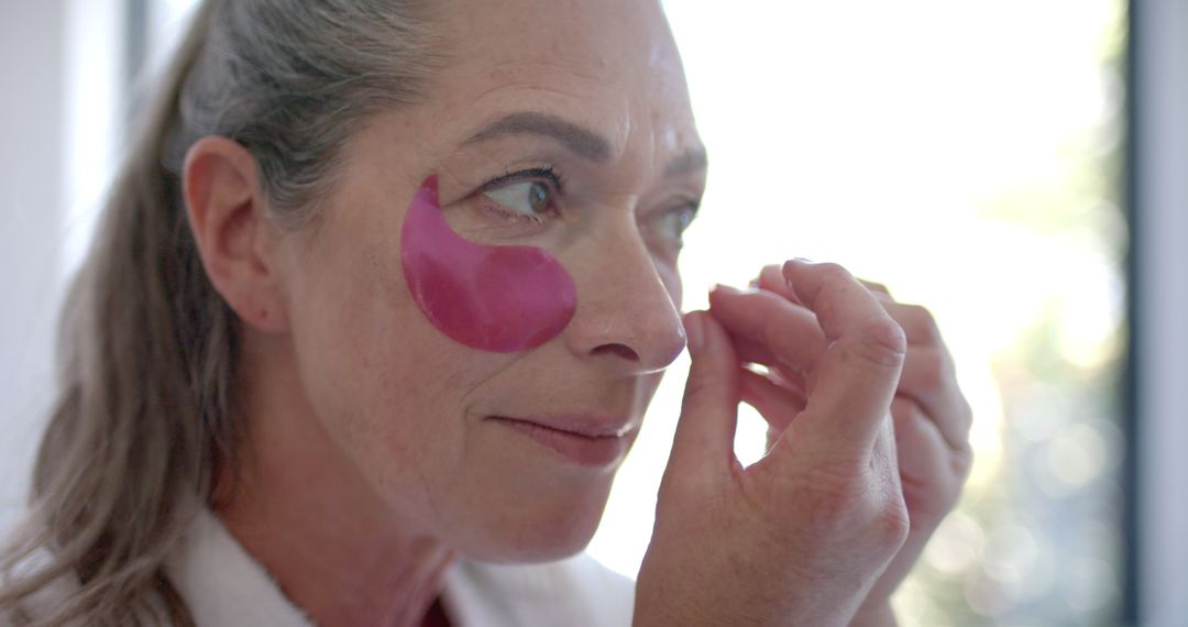 Mature Woman Applying Under-Eye Patches for Skincare Routine at Home