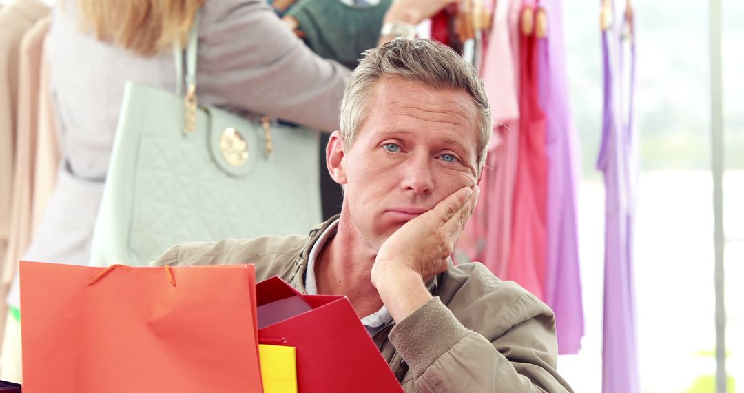 A middle-aged Caucasian man appears bored while holding shopping bags, with copy space - Free Images, Stock Photos and Pictures on Pikwizard.com