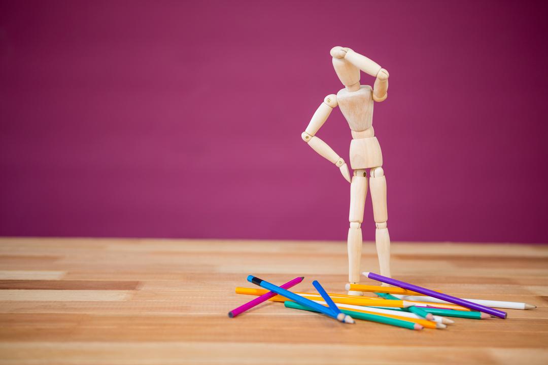 Wooden Figurine Pondering Over Scattered Colored Pencils - Free Images, Stock Photos and Pictures on Pikwizard.com