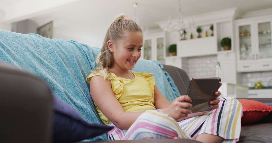 Happy Young Girl Watching Tablet at Home on Couch with Smiling Expression - Free Images, Stock Photos and Pictures on Pikwizard.com