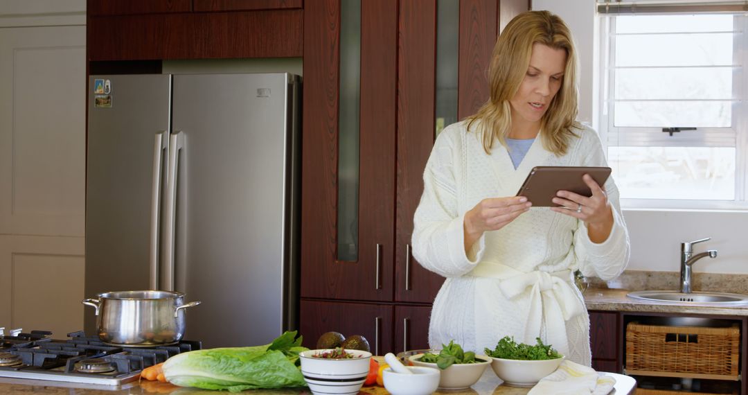 Woman in Cozy Robe Cooking with Tablet in Modern Kitchen - Free Images, Stock Photos and Pictures on Pikwizard.com