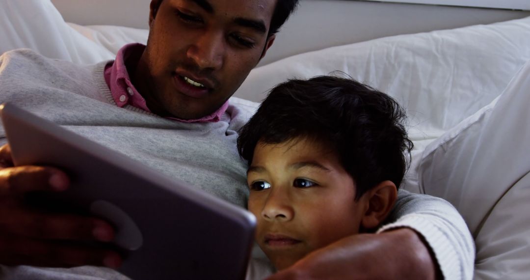 Father and Son Using Tablet Together on Bed - Free Images, Stock Photos and Pictures on Pikwizard.com