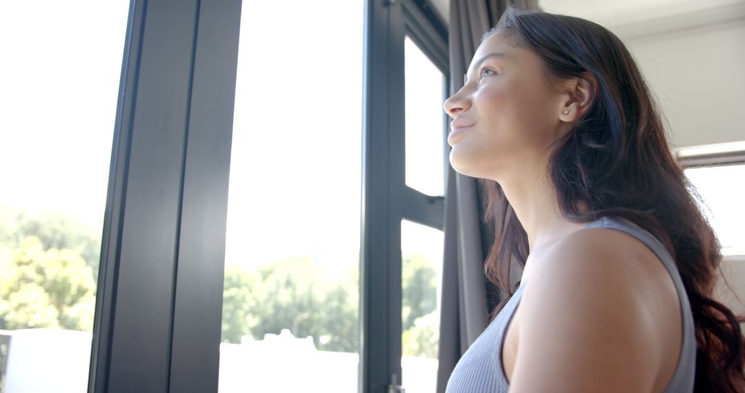 Young Girl Looking Out Sunlit Window Enjoying New Day