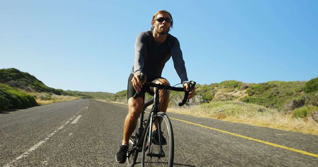 Athletic Man Biking on Open Road During Sunny Day - Free Images, Stock Photos and Pictures on Pikwizard.com