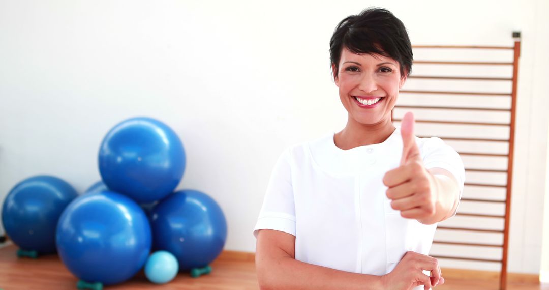 Smiling Female Physiotherapist Giving Thumbs Up in Gym - Free Images, Stock Photos and Pictures on Pikwizard.com