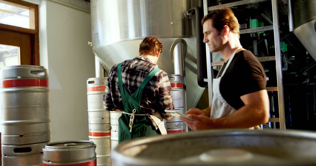 Two Workers in Brewery Inspecting Equipment and Kegs - Free Images, Stock Photos and Pictures on Pikwizard.com